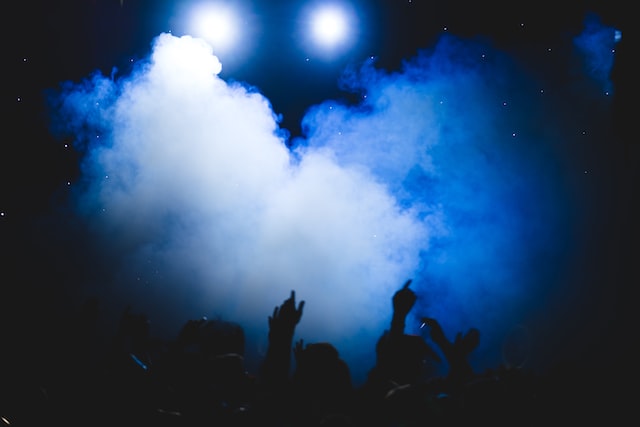 inside a dark nightclub with smoke emerging from a silhouette of hands reaching up to the air